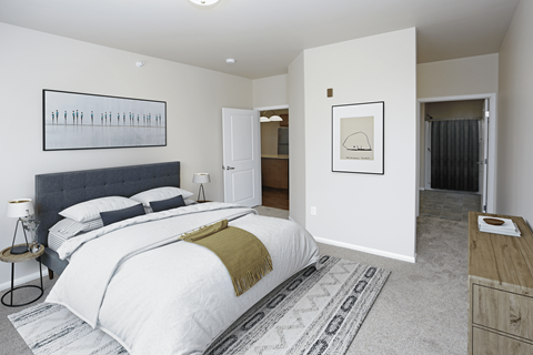 A bedroom with a large bed and a rug on the floor.