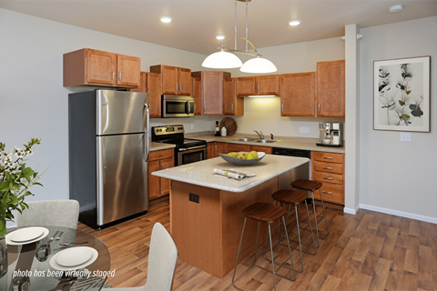 A kitchen with wooden cabinets and a stainless steel refrigerator.