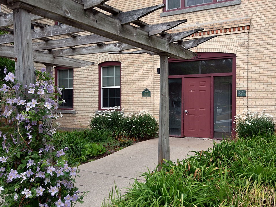 a historic brick building with a red door and a wooden pergola
