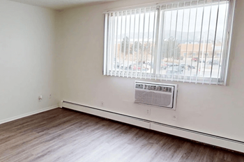 A room with a window and a wall-mounted air conditioning unit.