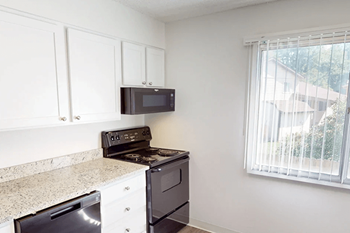A kitchen with white cabinets and a black stove top oven.