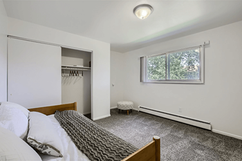 A bedroom with a bed, a window, and a closet.