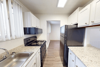 A kitchen with black appliances and white cabinets.