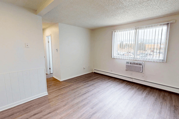 A room with a window and a door and wood plank style flooring.