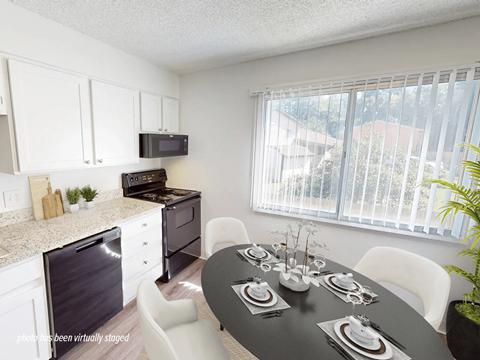 A black table is set for a meal in a white kitchen.