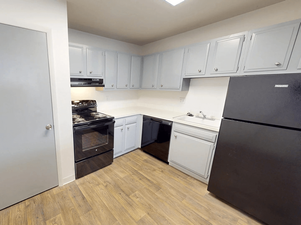 A kitchen with black appliances and white cabinets.