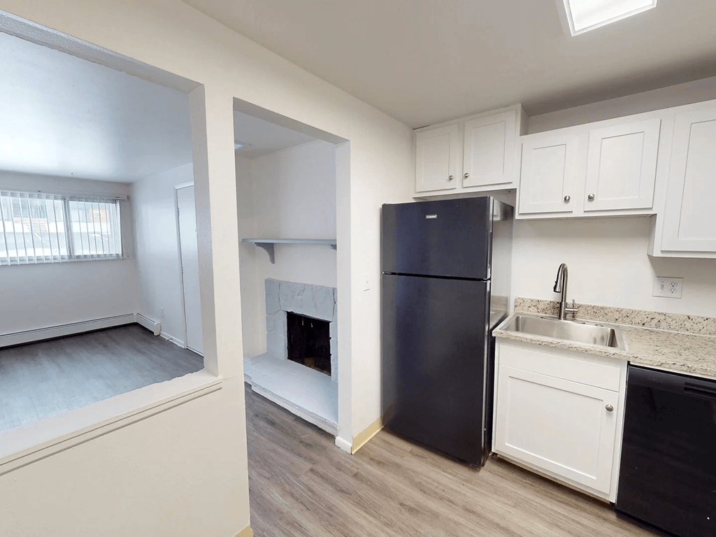 A black refrigerator sits in a kitchen next to a sink.