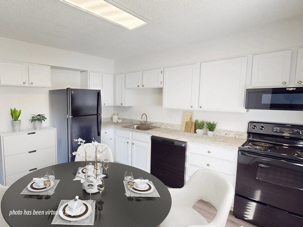 A kitchen with white cabinets and a black refrigerator.