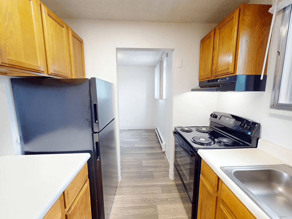 A kitchen with a black fridge and stove top oven.