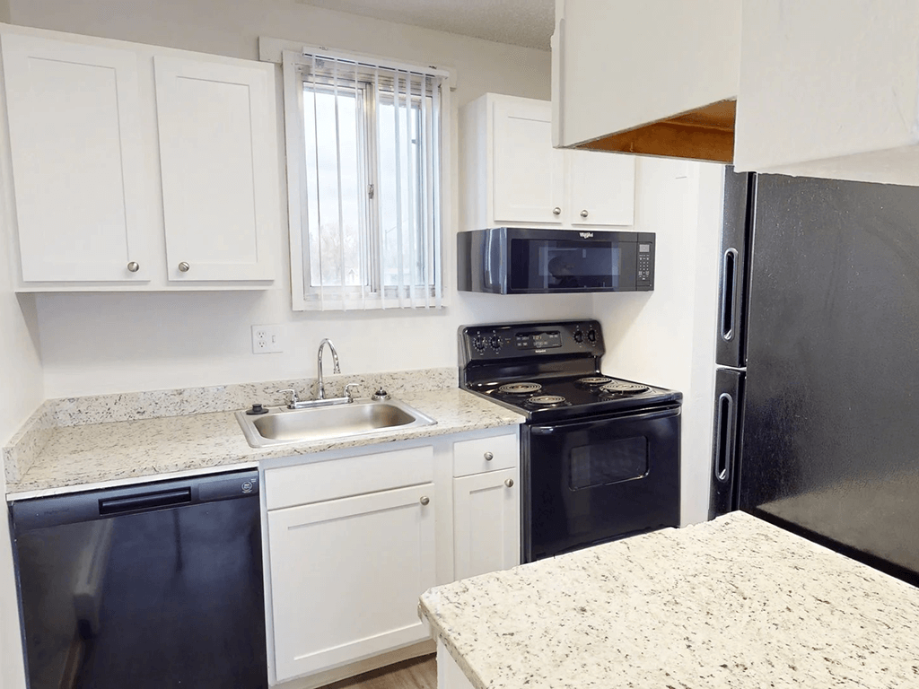A kitchen with black appliances and white cabinets.