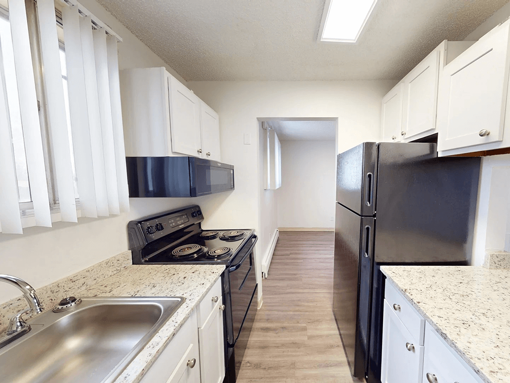 A kitchen with black appliances and white cabinets.