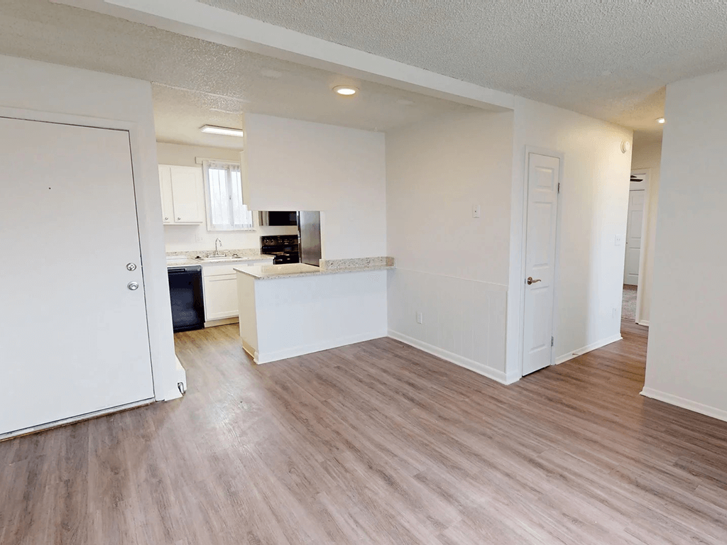 A kitchen with white cabinets and a countertop is visible from the living room.