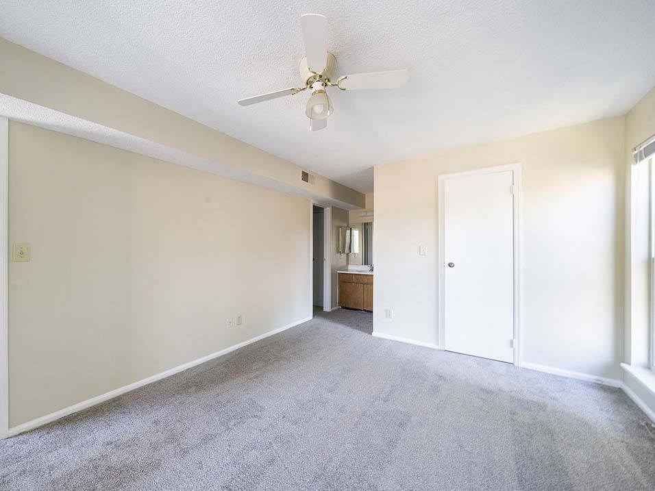 an empty living room with a ceiling fan