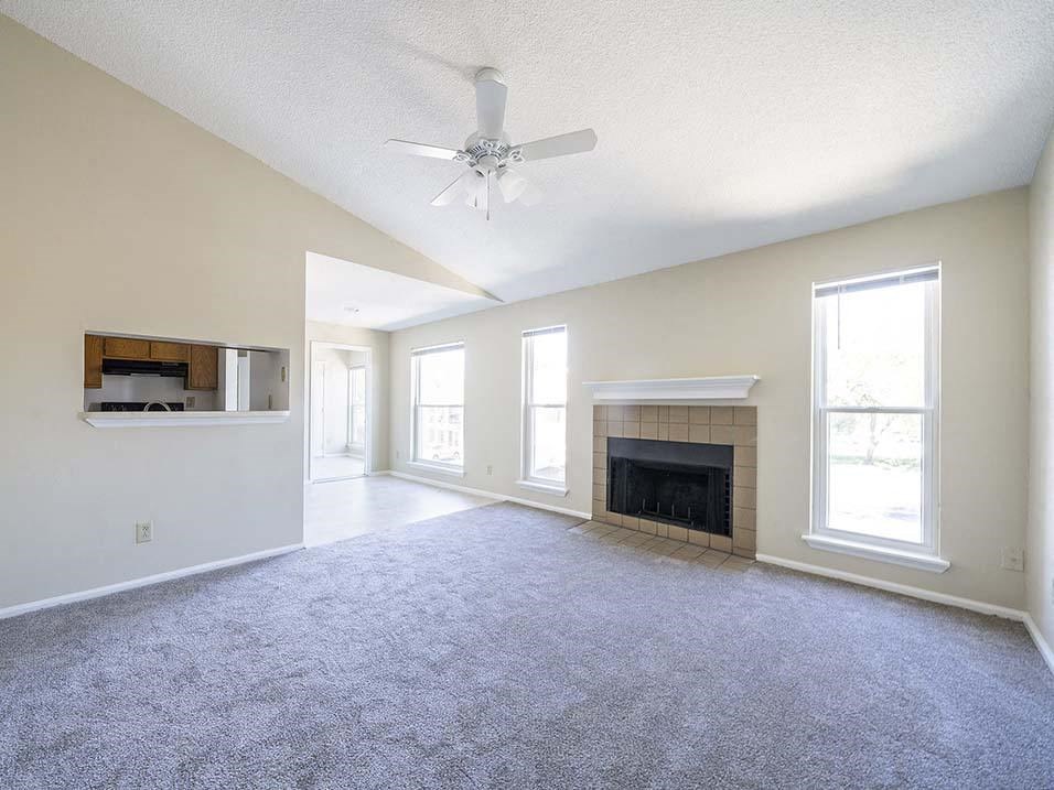 an empty living room with a fireplace and a ceiling fan