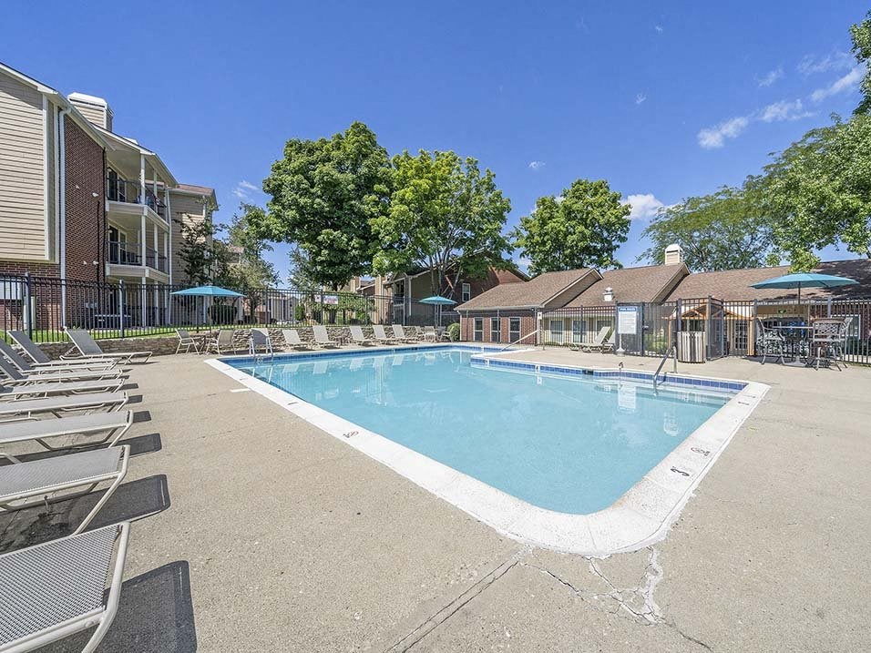 a swimming pool with chairs around it in front of a building