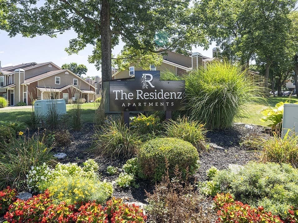 the residence apartments sign in front of a garden