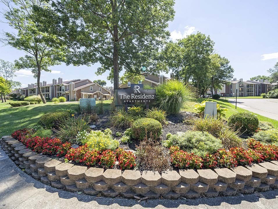 a flower garden in front of the residence sign
