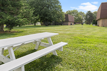 a white picnic table in the grass in front of a building