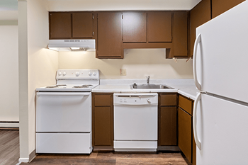 an empty kitchen with white appliances and brown cabinets