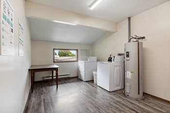a laundry room with washer and dryers and a table and a window