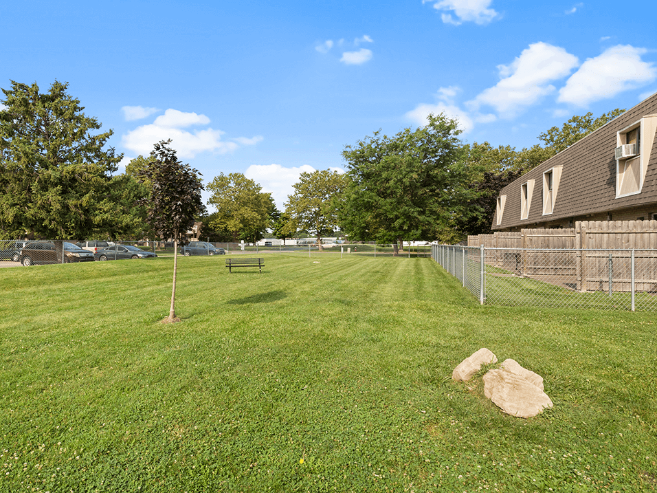 a fenced in dog park with apartments in the background
