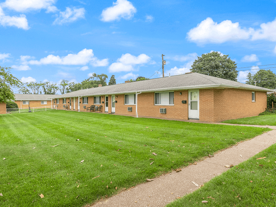 a brick building with a grass yard and a sidewalk