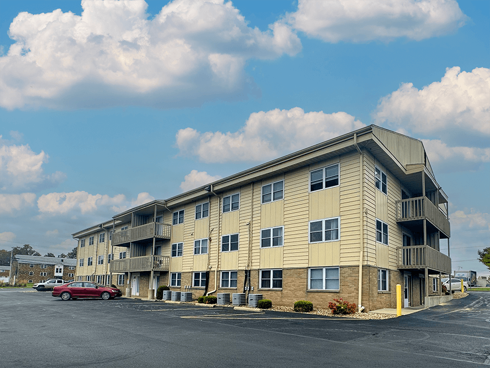 an apartment building with a red car parked outside