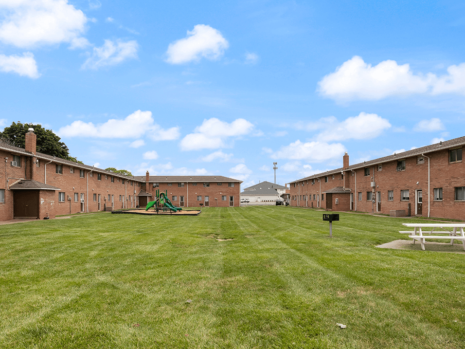 brick apartment building with a grassy field in front of it