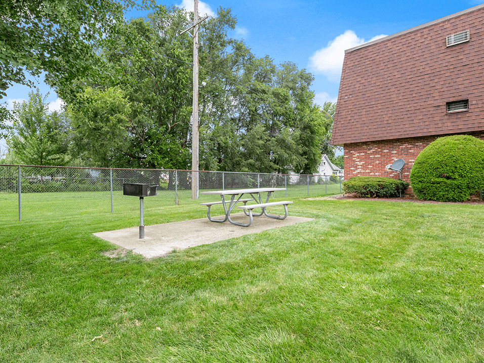 a picnic table in a park next to a chain link fence