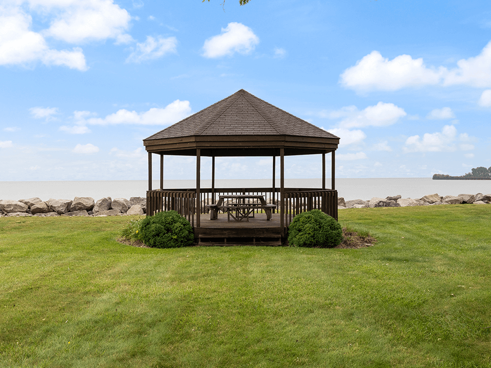 a gazebo with a table and chairs on a lawn near the water