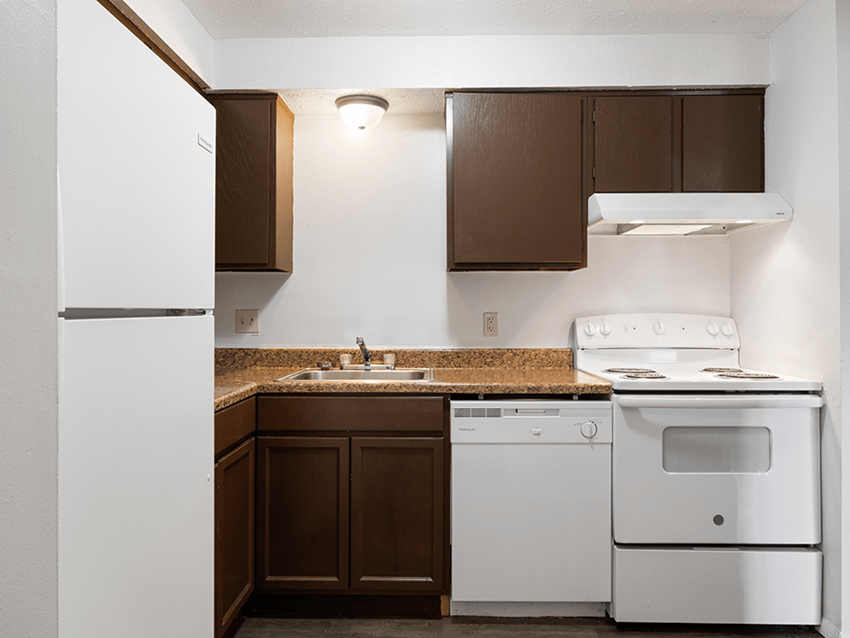 an empty kitchen with white appliances and a counter top