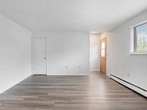 an empty living room with white walls and wood floors