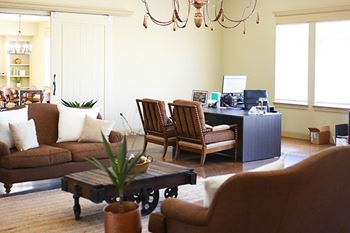 A living room with brown furniture and a chandelier.