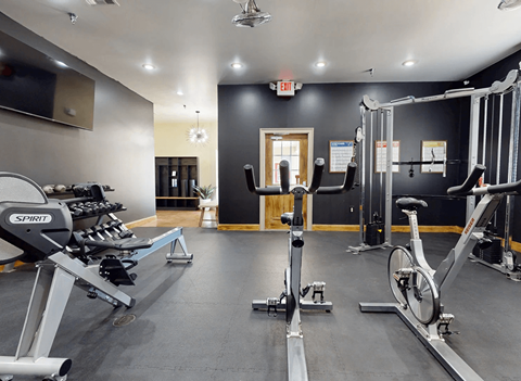 A gym with a variety of exercise equipment including treadmills, stationary bikes, and weight machines.