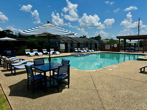 a swimming pool with a table and chairs and an umbrella