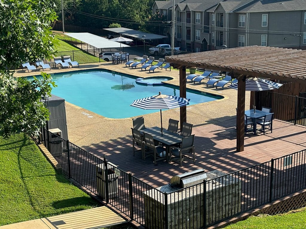 a large swimming pool with tables and umbrellas