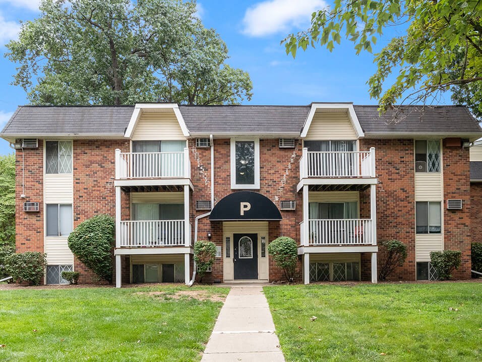 a red brick apartment building with a sidewalk in front of it