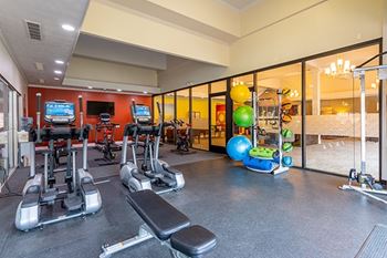 A gym with a variety of equipment including treadmills, exercise balls, and weight machines.
