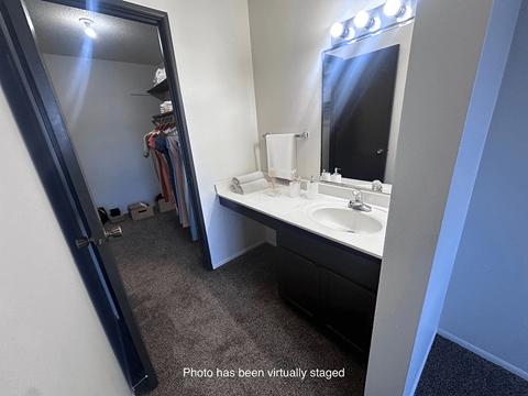 A bathroom with a sink, mirror, and a large mirror with lights above it.