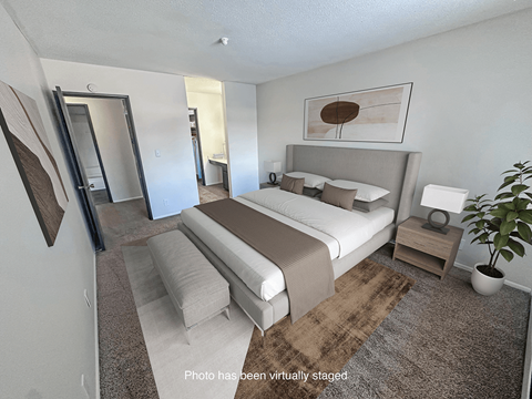 A bedroom with a bed, nightstand, and mirror.