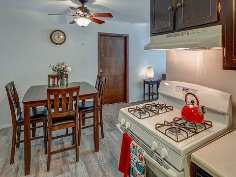 A kitchen with a white gas stove and a dining table with chairs.