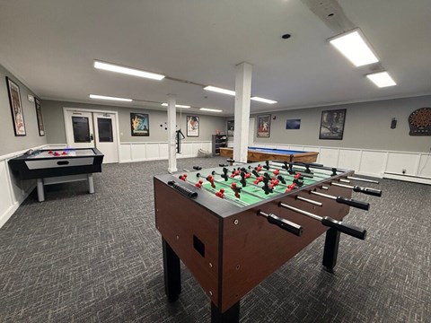 A foosball table is in the middle of a room with a pool table and a foosball table.