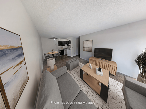 A living room with a grey couch and a painting on the wall.