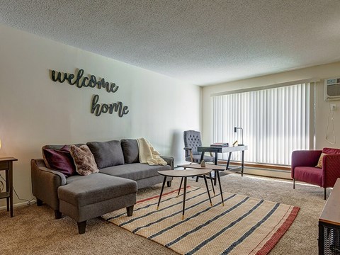 A living room with a grey sofa and a welcome home sign.