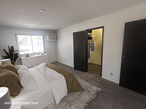 A bedroom with a bed, a wardrobe, and a window.