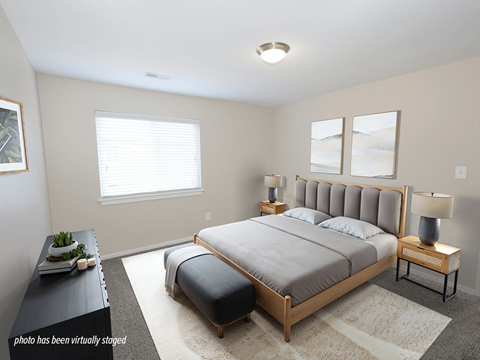 A bedroom with a large bed and a nightstand with a lamp.