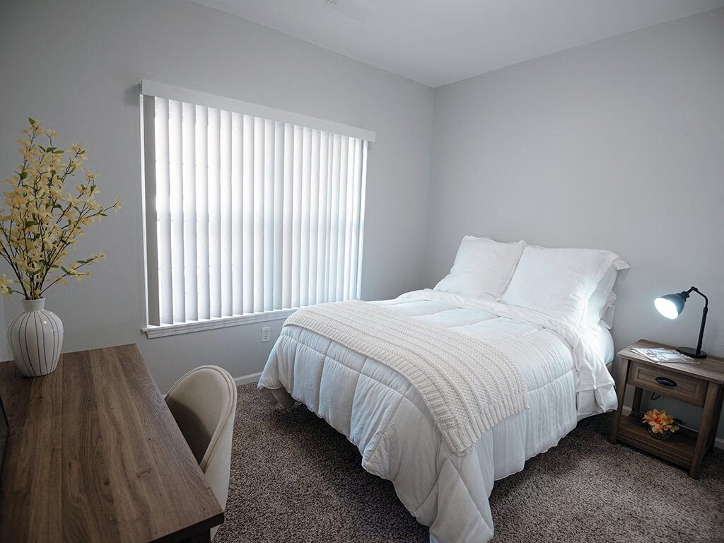 a bedroom with a bed and a desk and a window