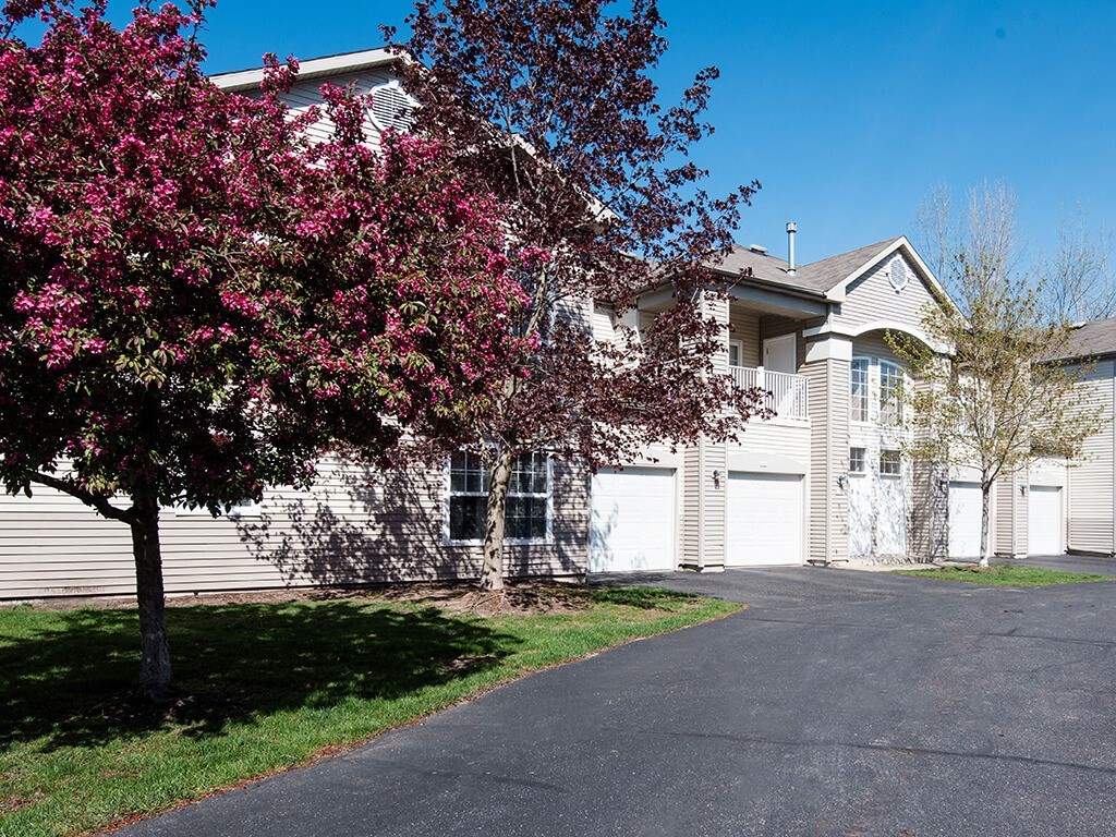 a tan apartment with a flowering tree in front of it