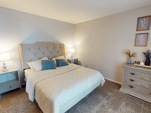A bedroom with a large bed and a nightstand with a lamp.