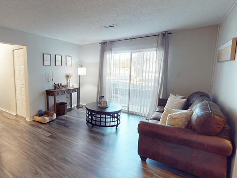 A living room with a brown leather couch and a glass coffee table.